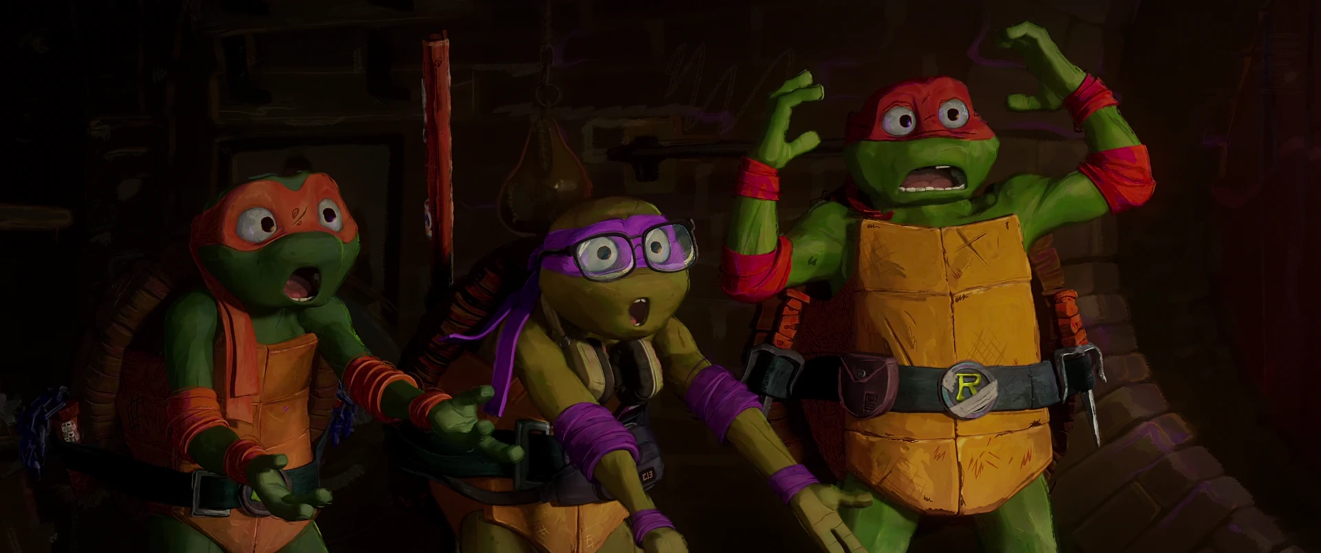 Michelangelo, Donatello and Raphael stand wide-eyed and alarmed inside the dimly lit sewer lair.