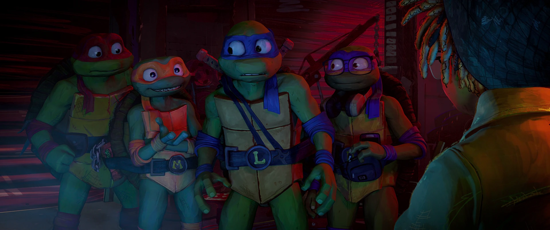All four Turtles stand facing April from behind, lit in warm red and blue tones in a dim urban corridor.
