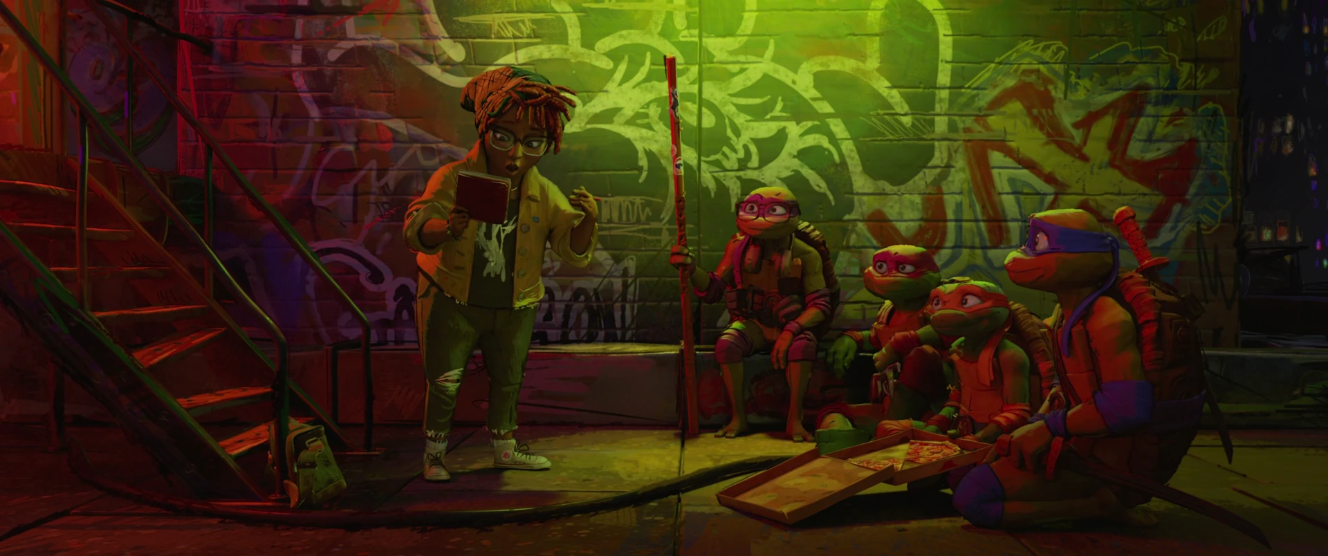 April reads from a notebook while three Turtles sit and listen against a graffiti-covered wall in green light.