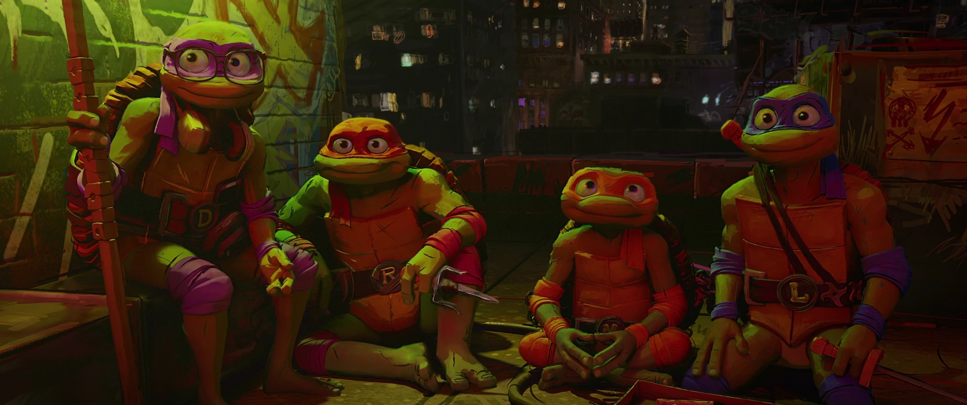 All four Turtles sit together against a graffiti wall at night, lit in warm amber, looking quietly vulnerable and young.