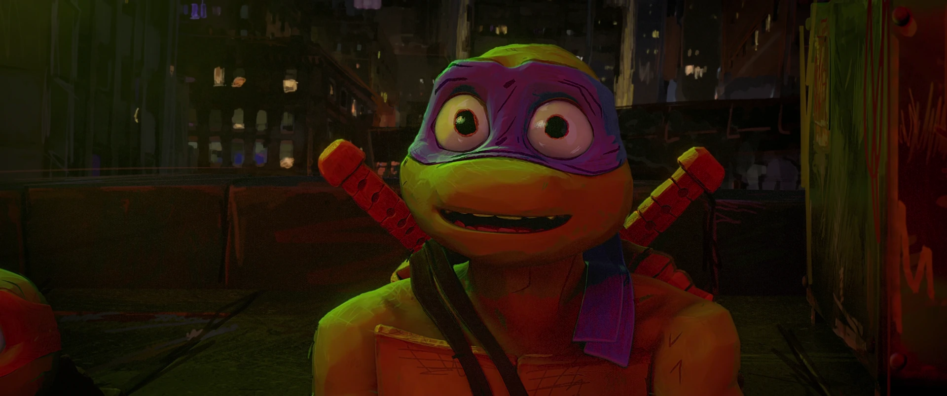 Donatello grins broadly in close-up, purple mask bright, lit warmly against a night city skyline.