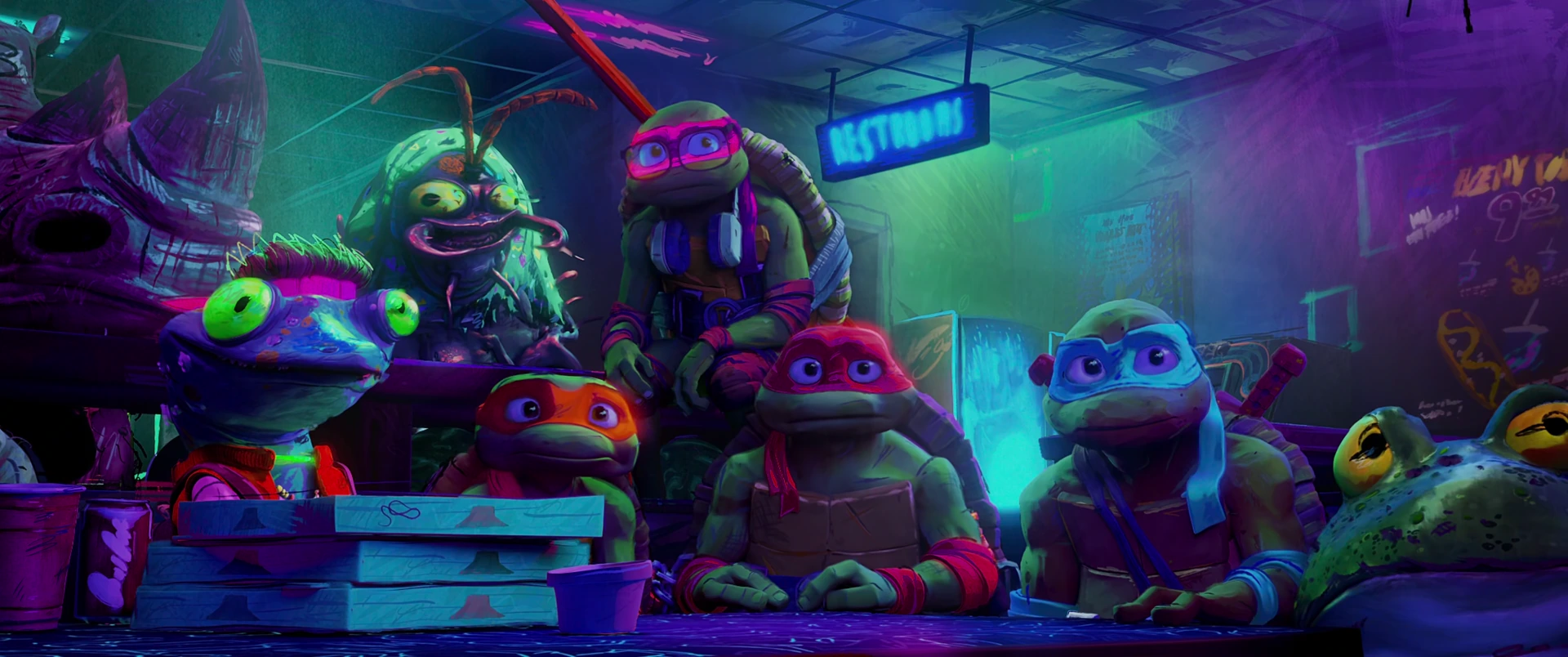 A wide group of mutants including all four Turtles sits around a table in the packed neon-lit hideout, listening intently.