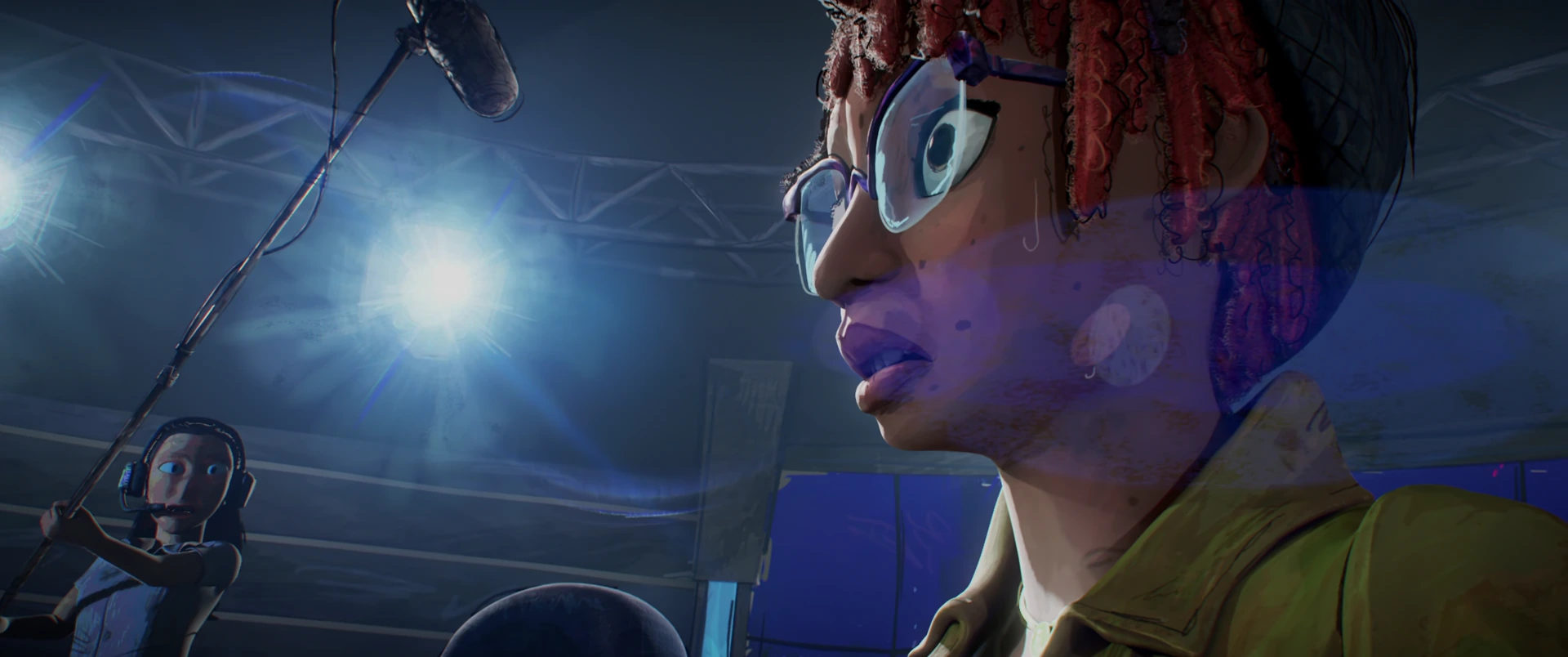 April speaks into a microphone under bright studio lights, glasses on and yellow jacket vivid.