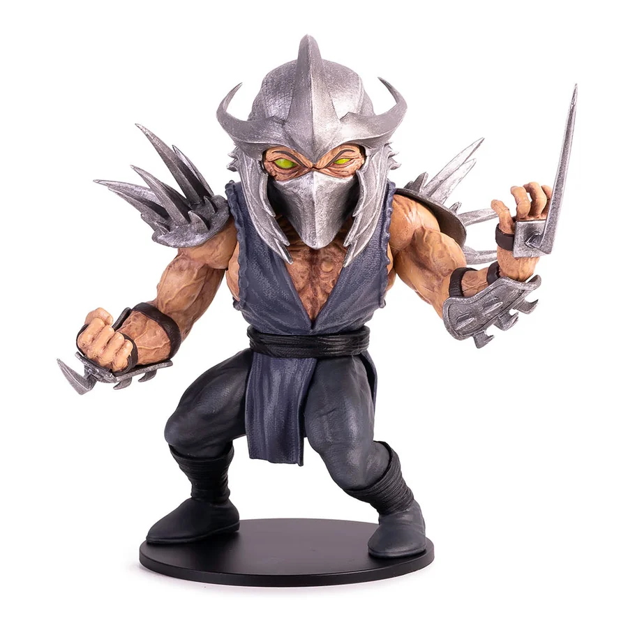 A small stylised Shredder figure with green eyes, an oversized helmet and exaggerated proportions, standing on a round black display base against a white background